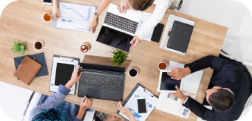 في صورة اجتماع، مجموعة من الأشخاص يعملون على أجهزة الكمبيوتر المحمولة، منشغلون بعملهم.